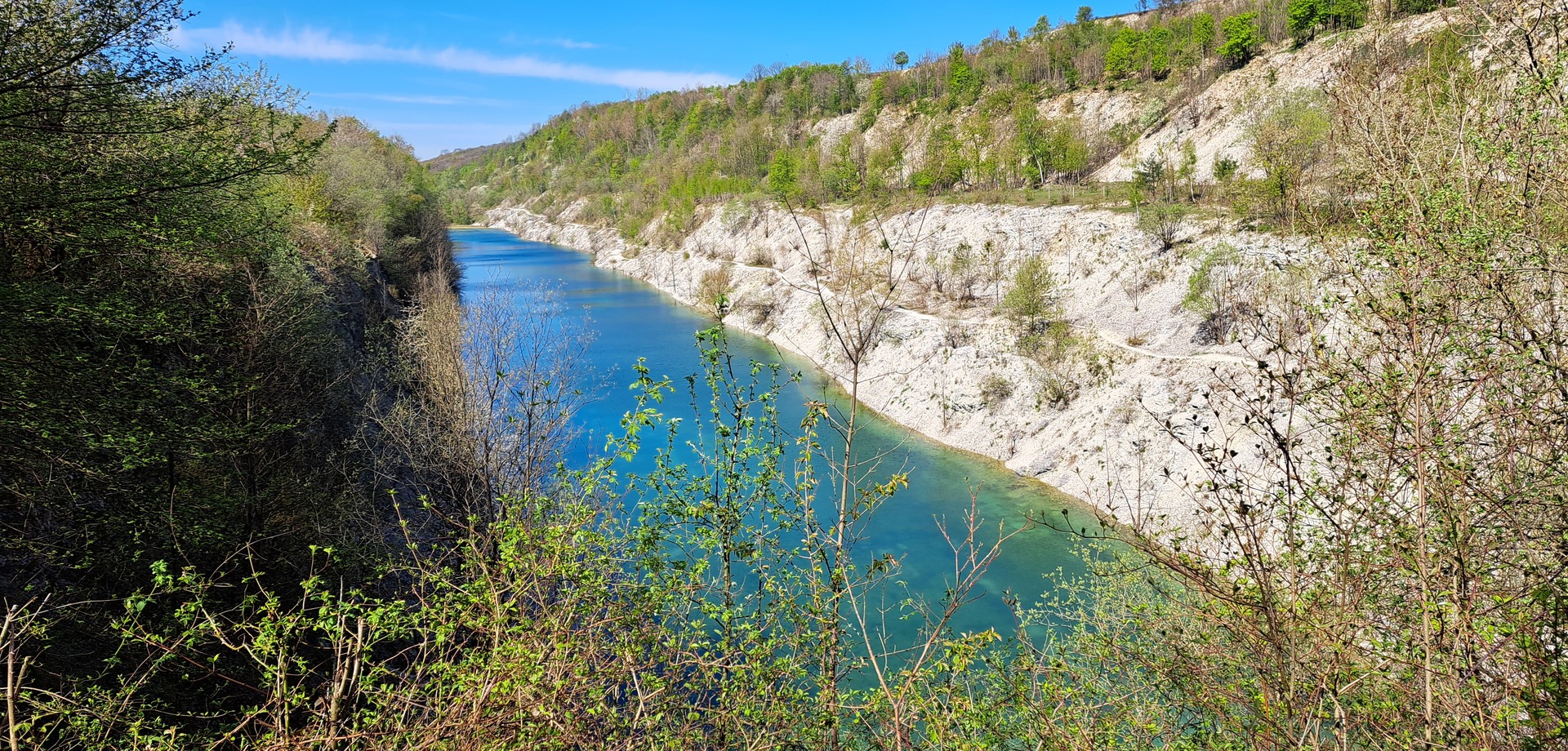 Ein türkisfarbener See zwischen steilen Kalksteinwänden und Bäumen und Sträuchern