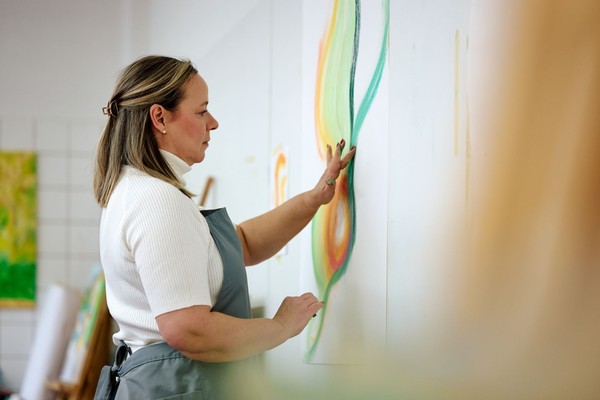 Eine Frau malt mit den Händen ein großes Bild an der Wand