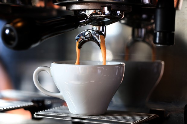 Kaffee läuft aus einer Kaffeemaschine in eine weiße Tasse.