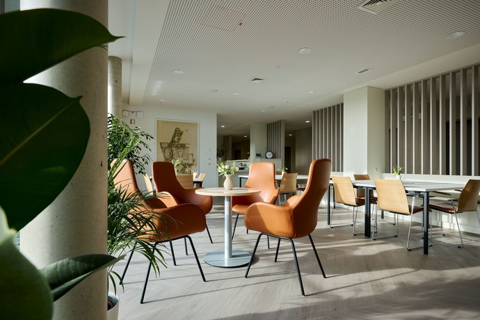 heller Aufenthaltsraum mit modernen, orangefarbenen Sesseln