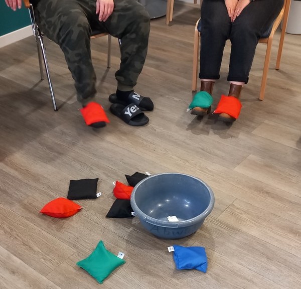 Zwei Menschen versuchen, Säckchen auf ihren Füßen zu balancieren.