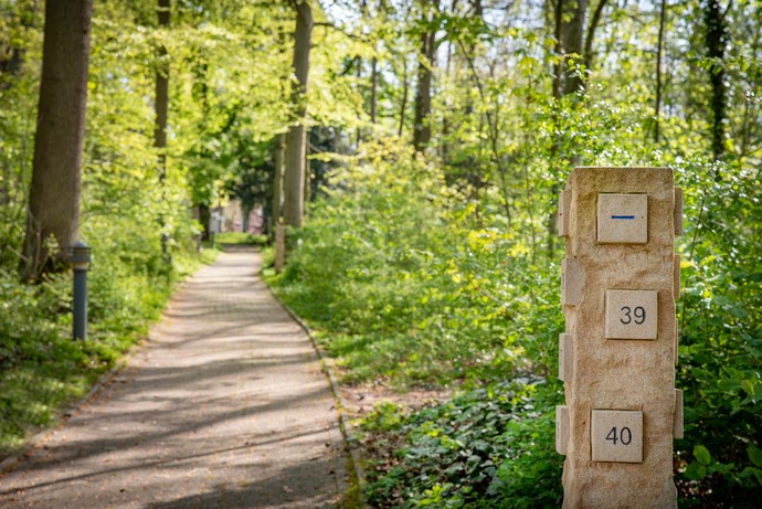 Eine Sandstein-Stele an einem Weg durchs Grüne