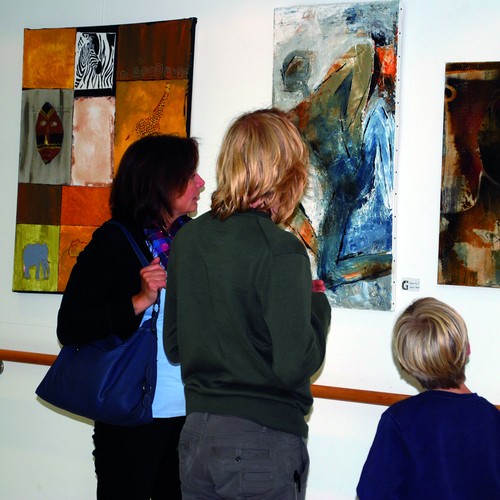 Zwei Frauen und ein Kind betrachten Bilder einer Ausstellung.