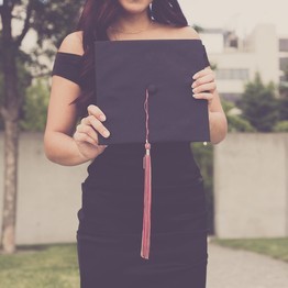 Eine Frau in einem schwarzen Kleid hält eine schwarze Mappe hoch