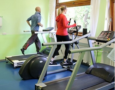 Zwei Menschen bewegen sich auf einem Laufband und Stepper