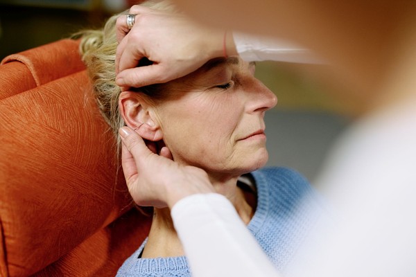 Kopf einer Frau, die Akkupunkturnadeln im Ohr hat