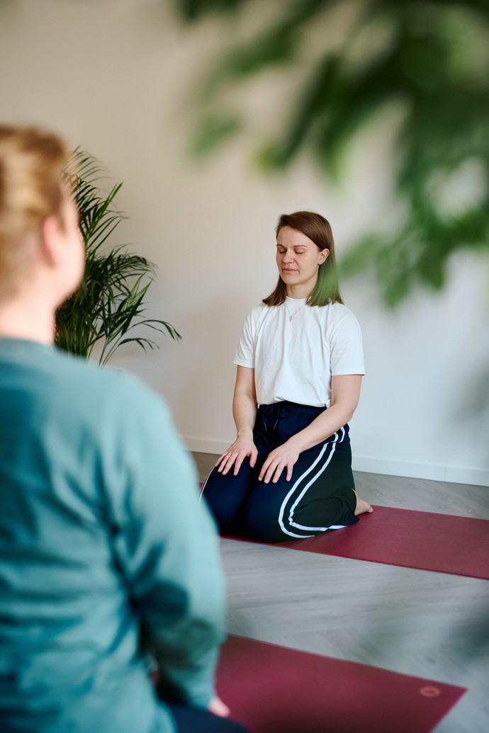 zwei Personen knien achtsam auf Yogamatten