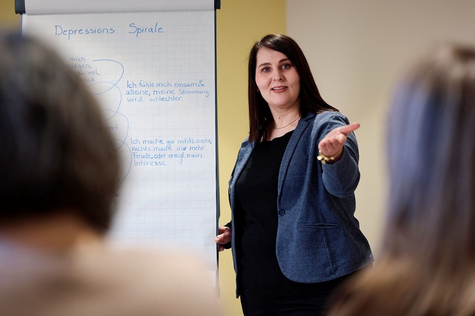 Frau mit dunklen Haaren steht an einem Flipchart und erklärt etwas