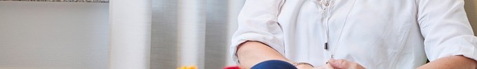 Eine lächelnde, junge Frau sitzt an einem Couchtisch im Gespräch