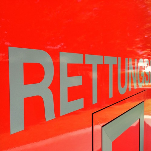 Schriftzug Rettungsdienst auf rotem Untergrund eines Krankenwagens