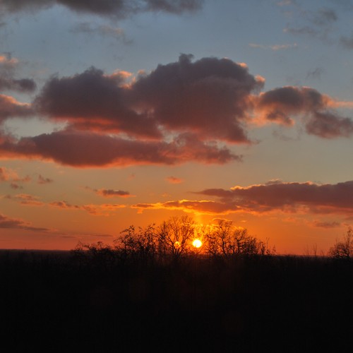 Ein leuchtend roter Sonnenuntergang mit dunklen Wolken.