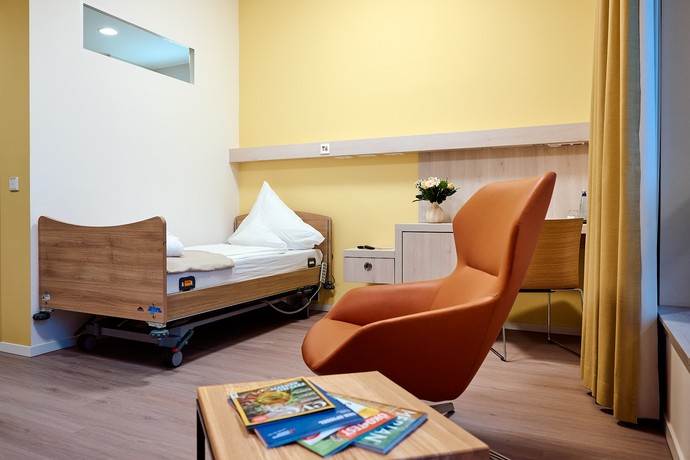 Modernes Zimmer mit orangenem Sessel vor einer gelben Wand