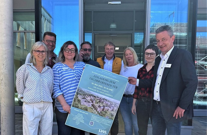 Personen halten ein Plakat vor einem neuen Gebäude