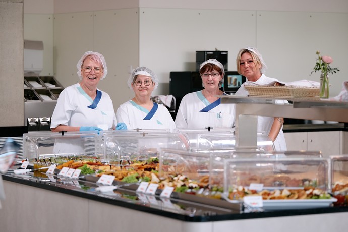 Vier Personen vom Küchenteam stehen hinter einem Buffet