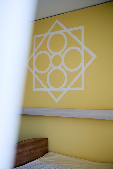gelbe Wand mit einem weißen Ornament (vergrößerte Bildansicht wird geöffnet)
