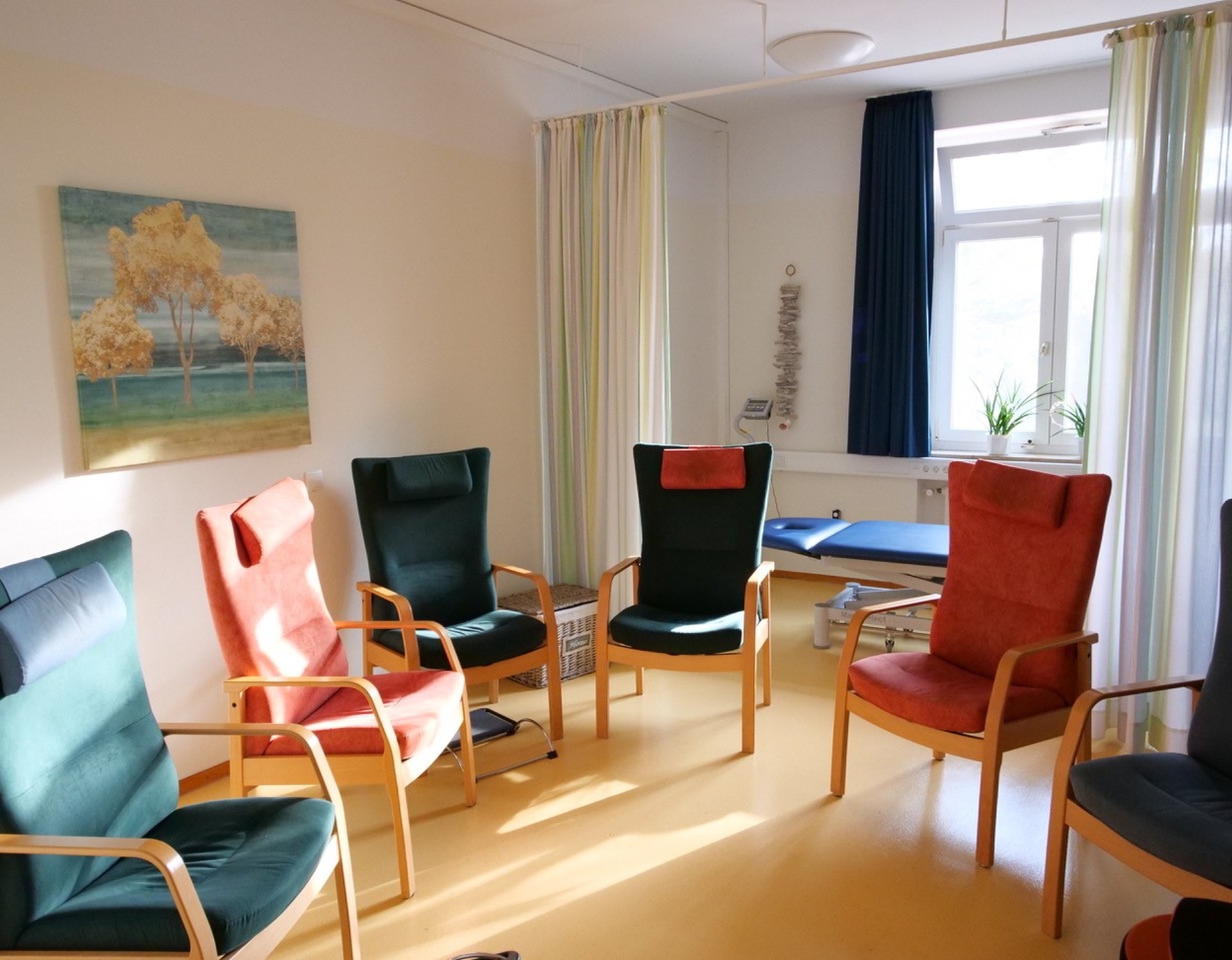SIeben hohe Stühle in verschiedenen Farben stehen in einem sonnenbeschienenen Raum im Kreis. Foto: Dr. Bernward SIegmund