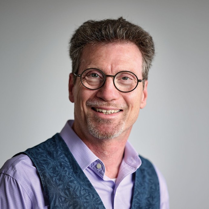 Ein Mann mit kurzen Haaren und Brille lächelt in die Kamera