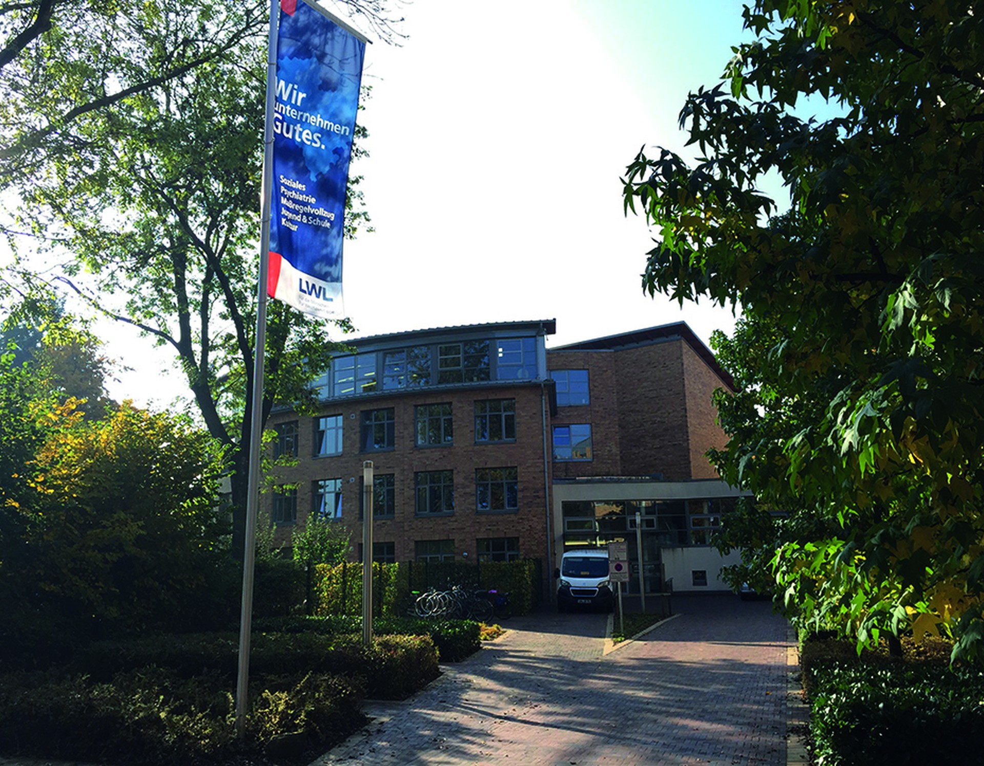 Ein vierstöckiges Gebäude mit großen Fenstern, davor weht eine blaue LWL-Flagge.Ein weißer Transporter steht vor dem Haus. Foto: Dr. Jörg WIttenhaus