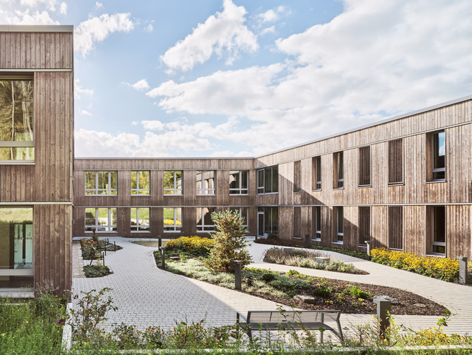 flaches Gebäude mit Holzfassade und Garten