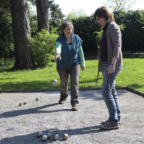 Zwei Frauen spielen Boule. Eine von ihnen wirft gerade eine silberne Kugel. Foto: Iris Wolf